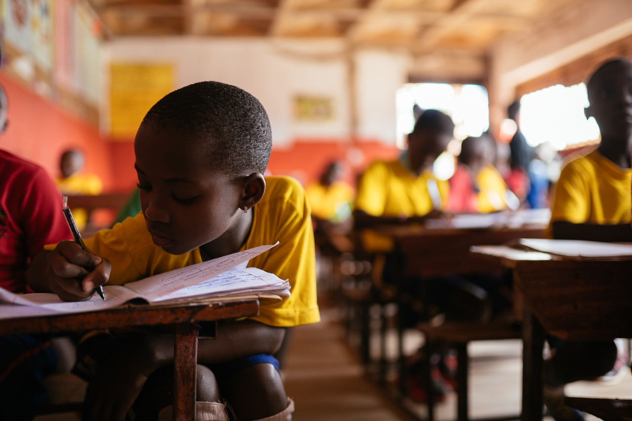 student in uganda writing at her desk
