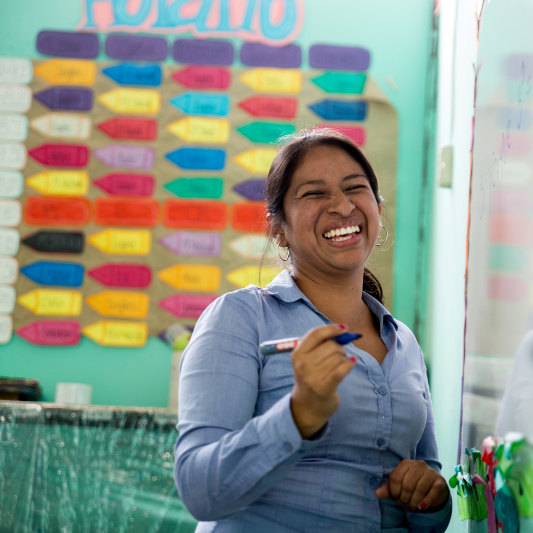 school proprietor smiling in front of a chalk board
