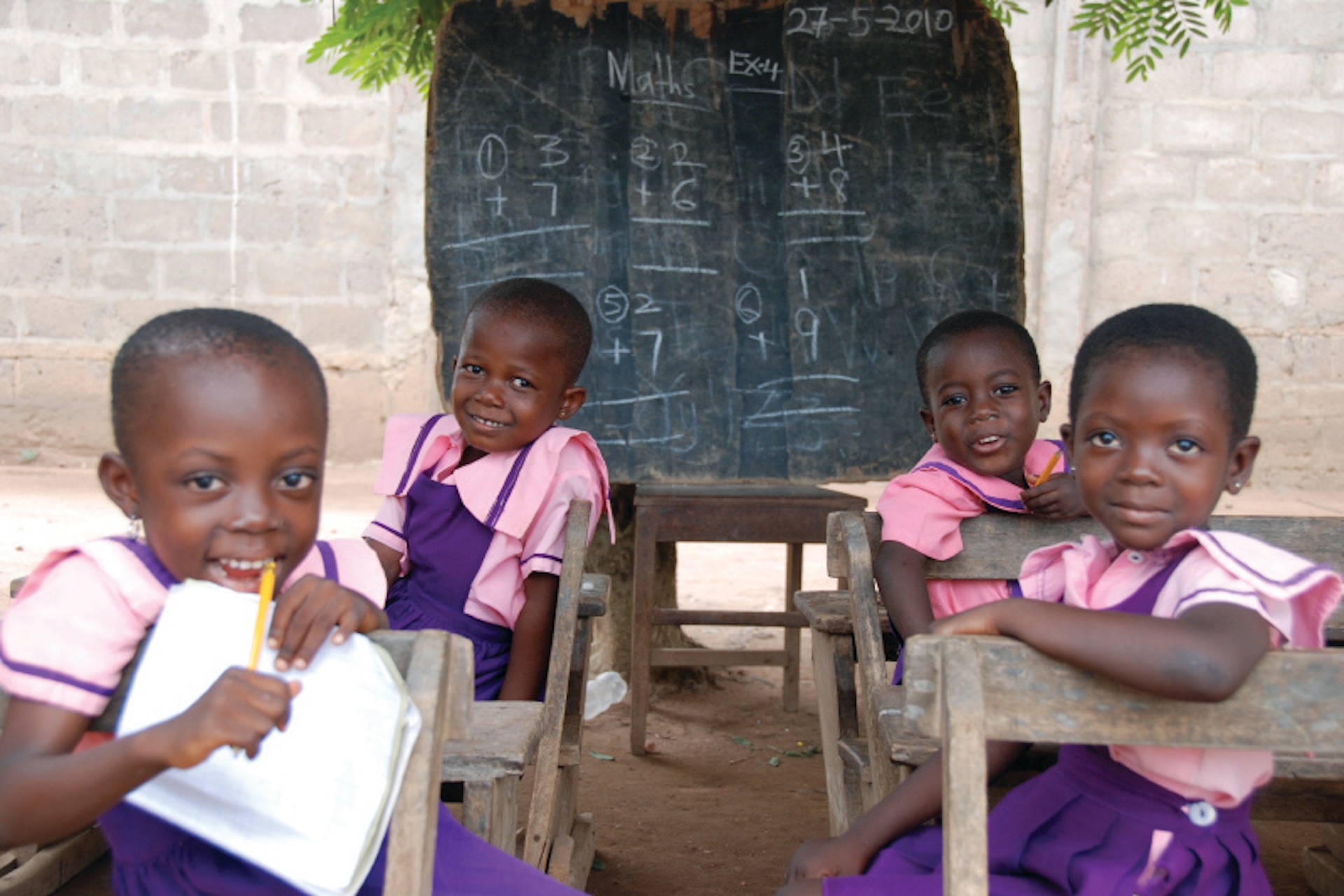young students in africa in front of a chalkboard with mathematics on it